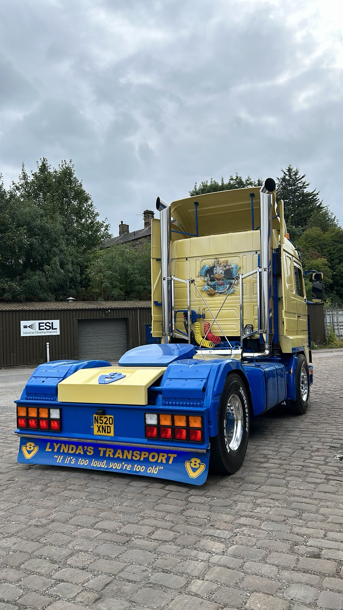 Rear view of a classic yellow and blue Lynda's Transport tractor unit